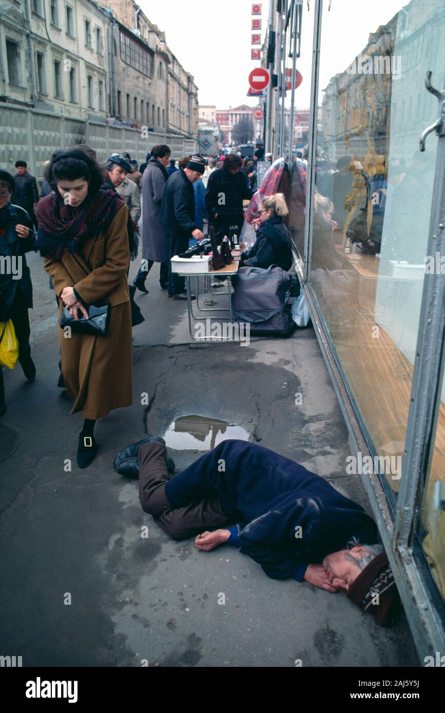 Senzatetto uomo addormentato sul marciapiede sul Strastnoy Bul'var (Street), vicino a Pushkin Square nel centro di Mosca, RU. 1993. Foto Stock