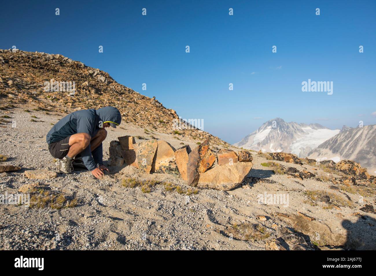 L'escursionista costruisce una parete di roccia per fornire becco di vento in campeggio. Foto Stock