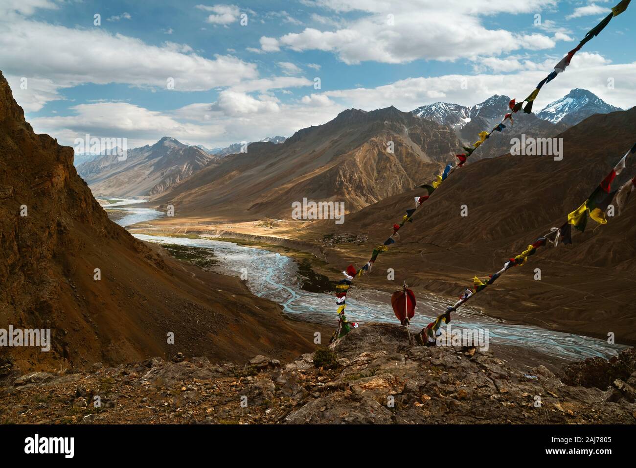 La Spiti fiume si snoda attraverso la valle di Spiti fiancheggiato dalla alta Himalaya e bandiere da preghiera buddista in una bella giornata d'estate nei pressi di Kaza, India. Foto Stock