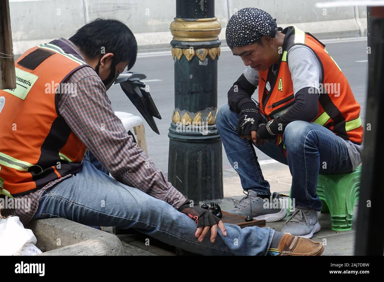 Bangkok, Tailandia - 21 dicembre 2019: moto taxi driver giocando in attesa accanto ai clienti. Foto Stock
