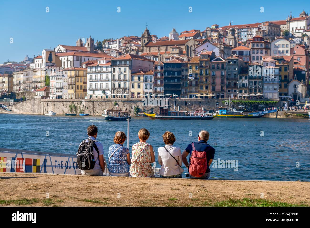 Turisti che si siedono sulle rive del fiume Douro godendo la vista attraverso l'acqua con la variopinta città di Porto, Portogallo. Fotografia: Tony Taylor Foto Stock