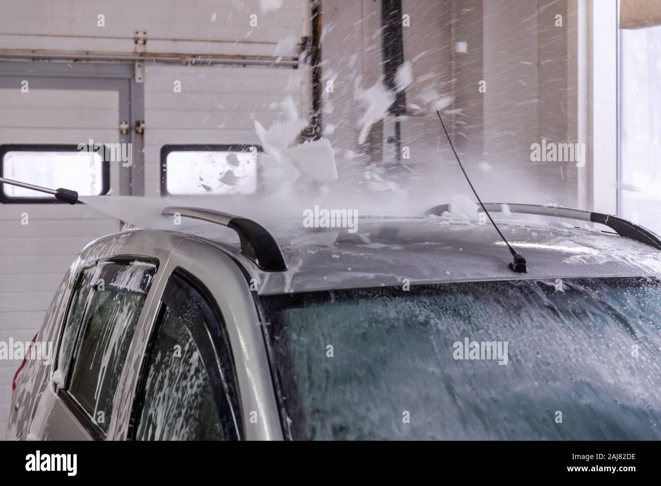 Piscina auto lavaggio auto. Processo di rimozione di schiuma di sapone dal tetto del veicolo con acqua ad alta pressione - flusso di close-up vith messa a fuoco selettiva e motion Foto Stock