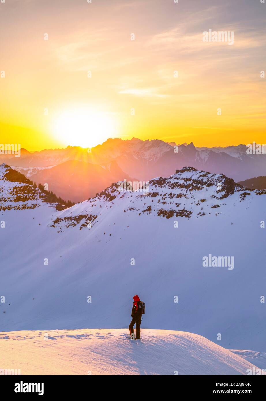 Escursionista in piedi nella neve sulla montagna, osservare il tramonto Foto Stock