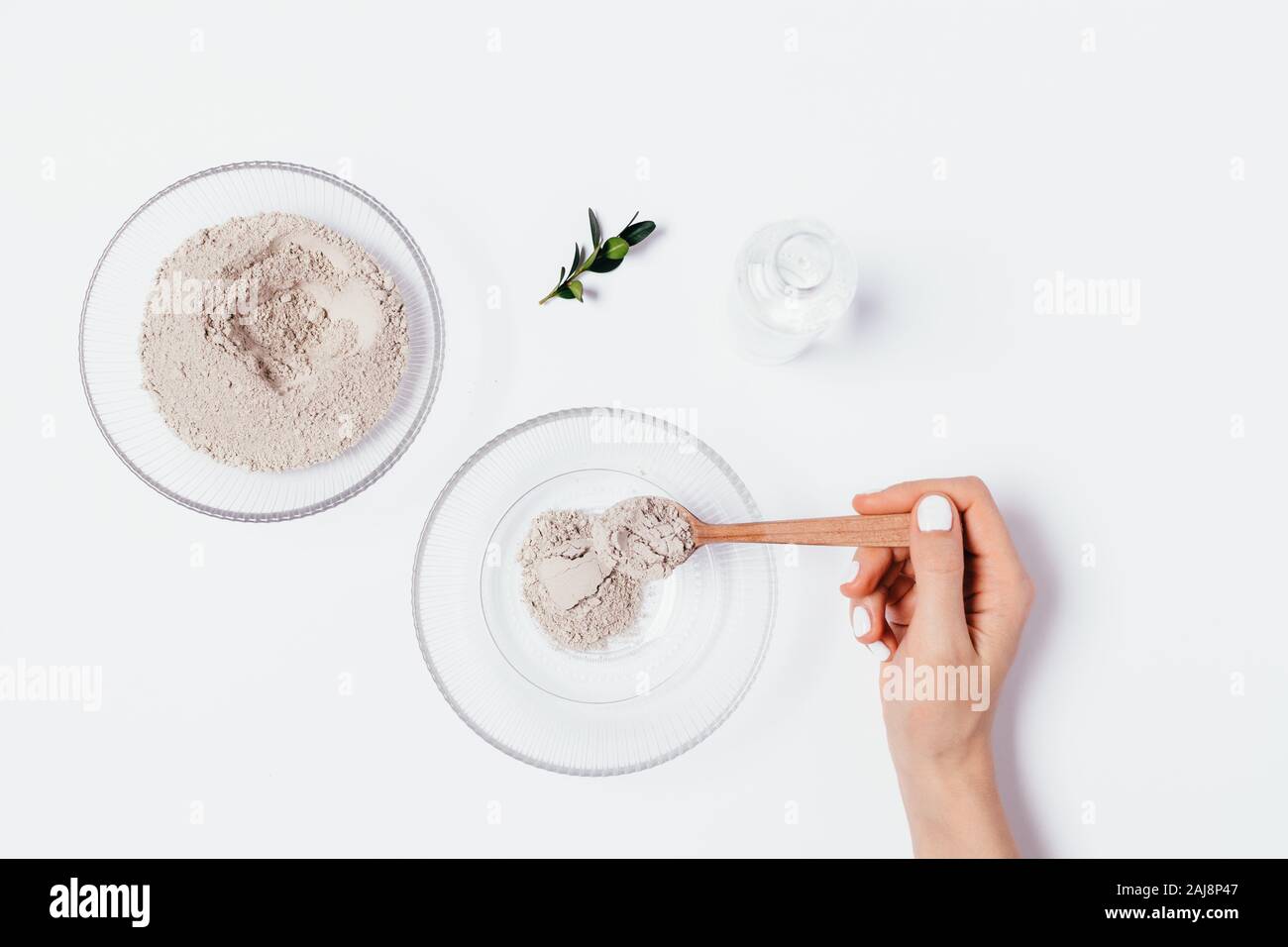 Donna di colata a mano cucchiaio di argilla in polvere in un recipiente per rendere semplice acqua in base detersione maschera facciale, laici piatta Foto Stock