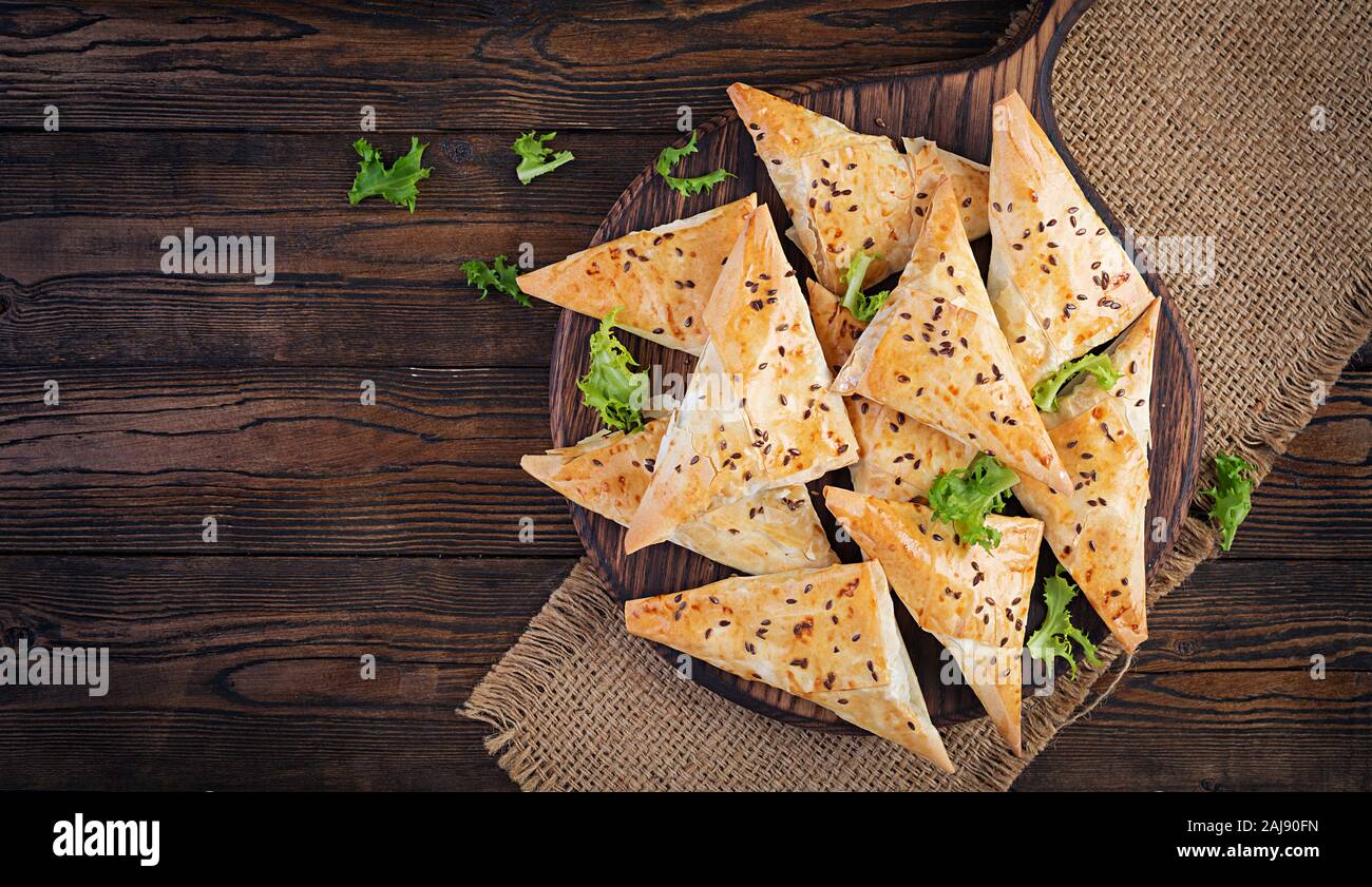 Cibo asiatico. Samsa (samosa) con filetto di pollo e formaggio su sfondo di legno. Vista superiore Foto Stock