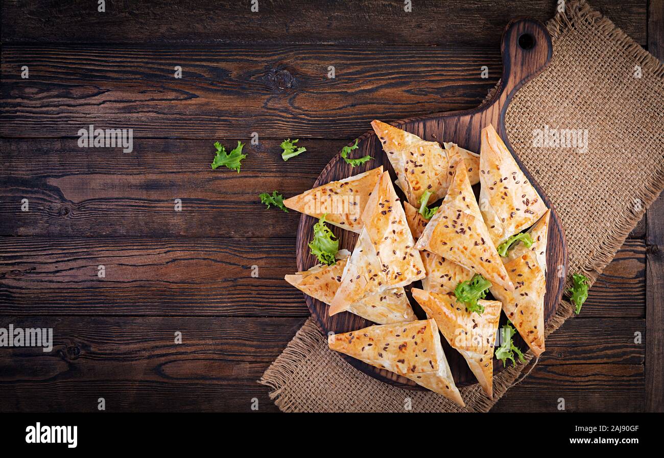 Cibo asiatico. Samsa (samosa) con filetto di pollo e formaggio su sfondo di legno. Vista superiore Foto Stock
