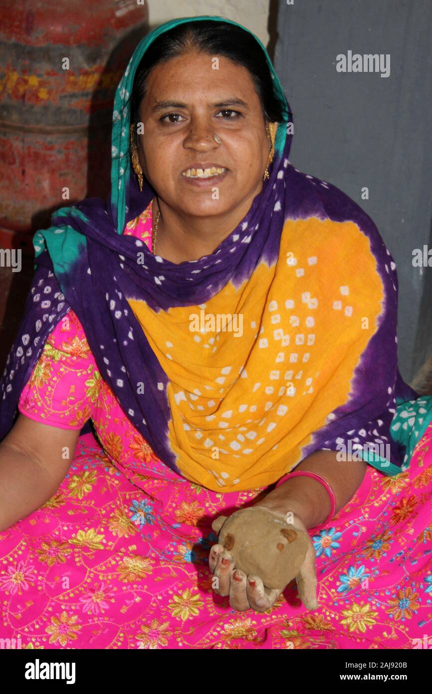 Donna del Lohar / Luhar comunità nel villaggio Nirona, grande Rann di Kutch, Gujarat, India detiene coperti di fango campana in rame per essere cotto in un forno. Foto Stock
