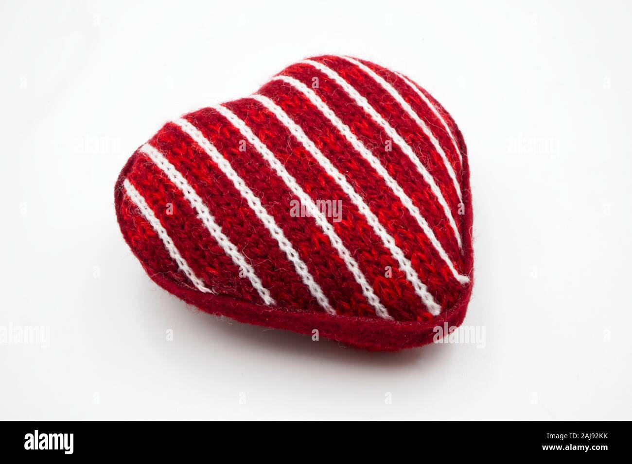In tessuto rosso cuore con strisce bianche, isolato su bianco. Felice il giorno di San Valentino Foto Stock
