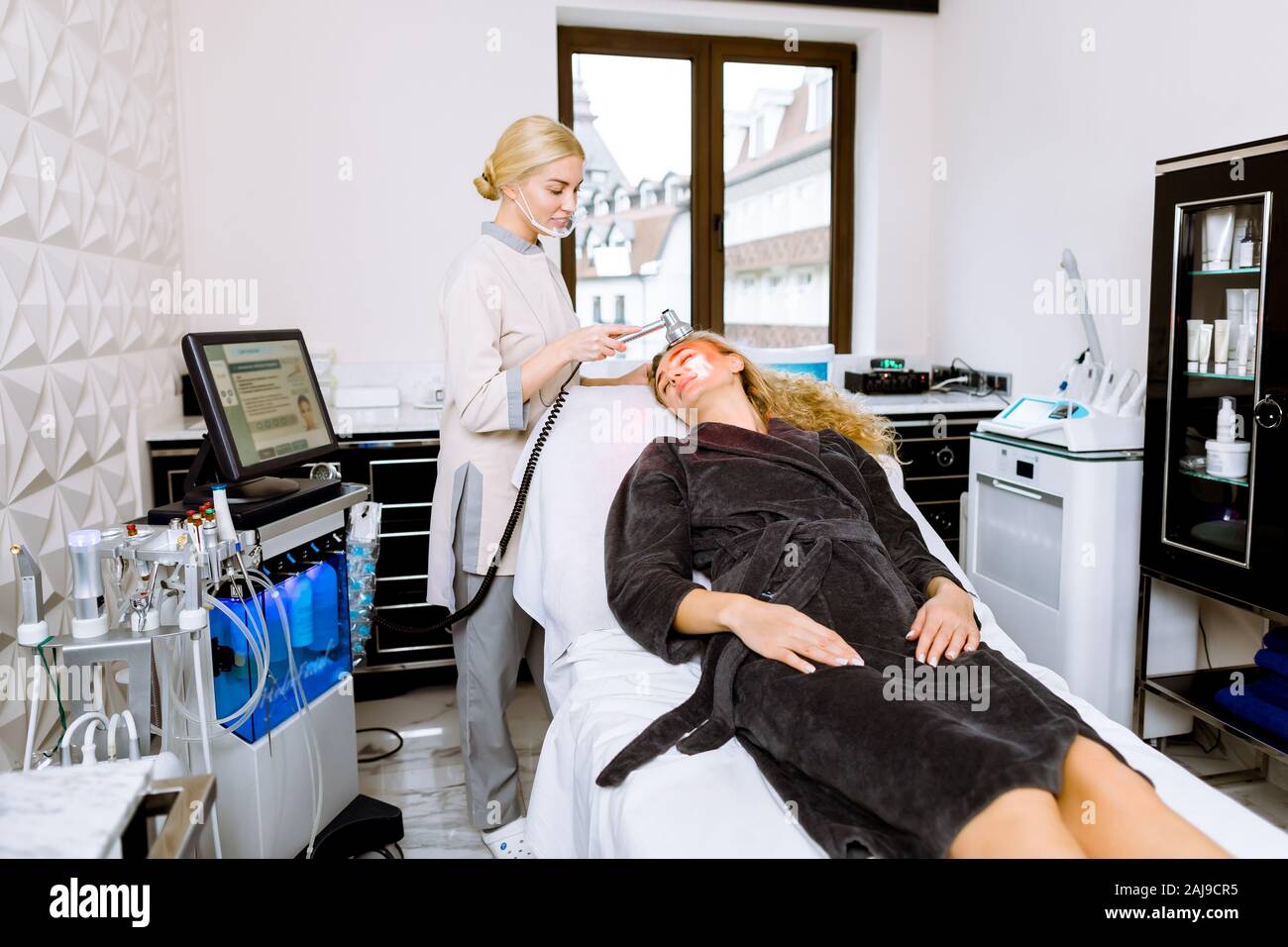 Donna dottore facendo luce LED rossa la terapia al giovane donna in clinica di bellezza, foto del viso la terapia per la pelle. Anti-trattamenti di invecchiamento, foto ringiovanimento pro Foto Stock