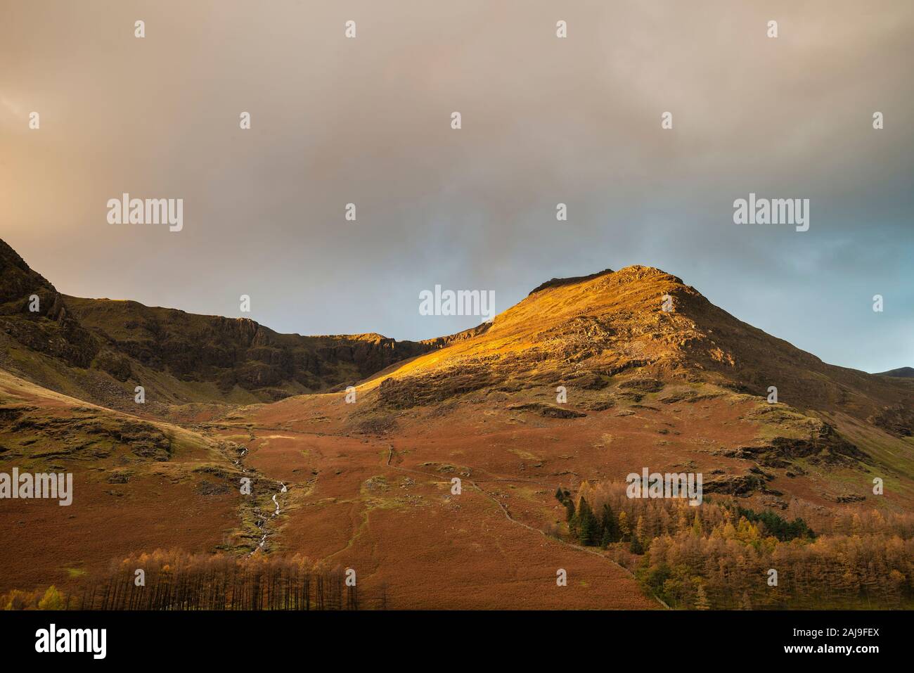 Incredibile epic Autumn Fall paesaggio Buttermere nel Lake District con una bella mattina presto la luce del sole giocando attraverso le colline e le montagne Foto Stock