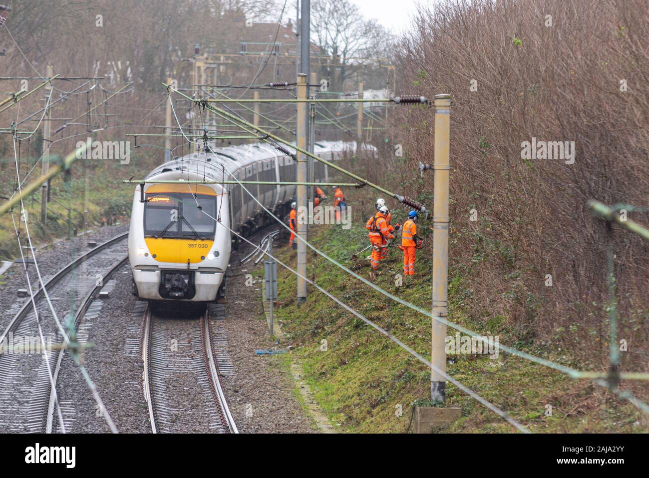 Lavoratori RailScape tagliare vegetazione vicino alla pista del C2C ferrovia in Southend on Sea, Essex, Regno Unito. Modo permanente per equipaggio con il treno che passa Foto Stock
