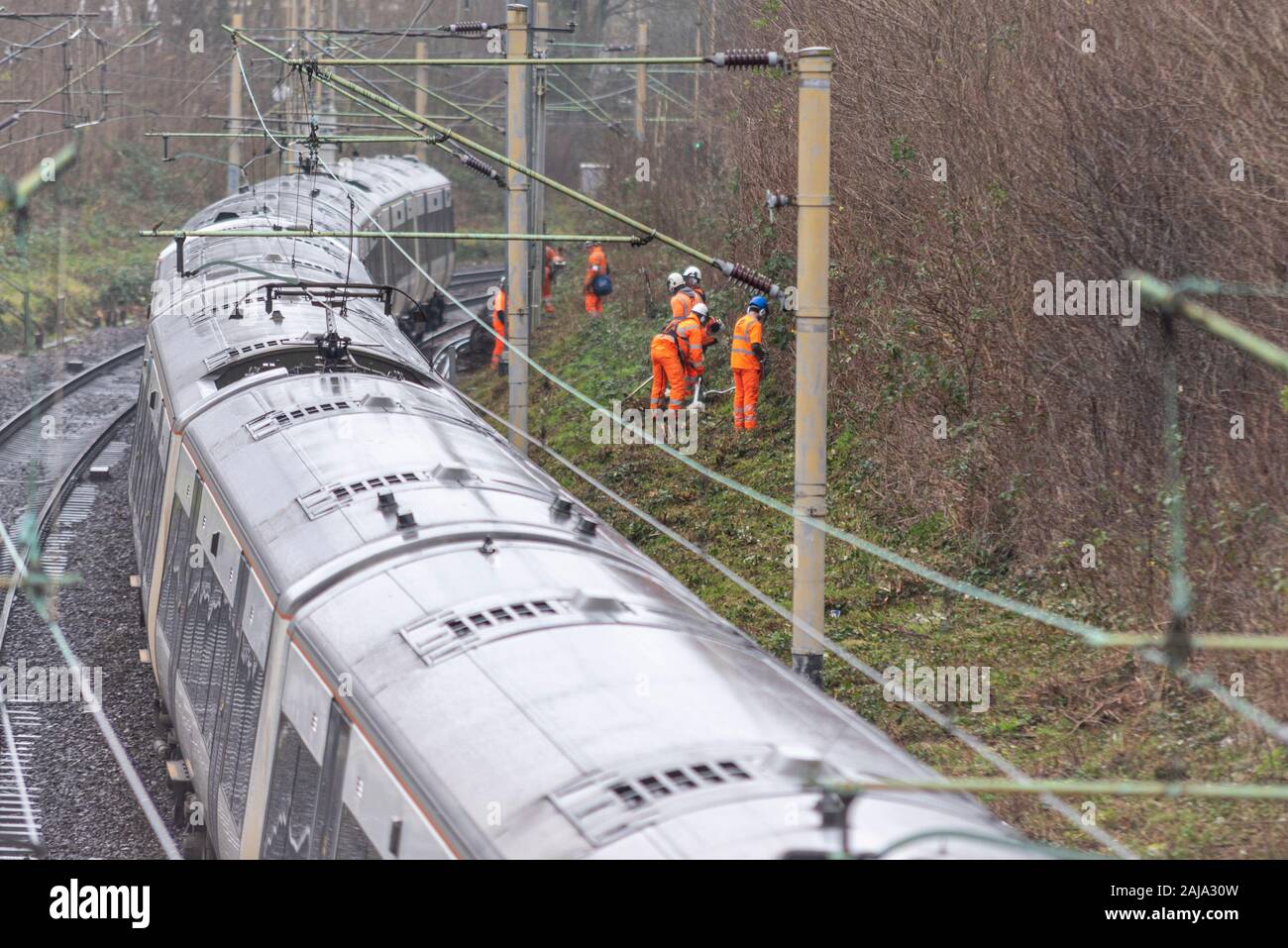 Lavoratori RailScape tagliare vegetazione vicino alla pista del C2C ferrovia in Southend on Sea, Essex, Regno Unito. Modo permanente per equipaggio con il treno che passa Foto Stock