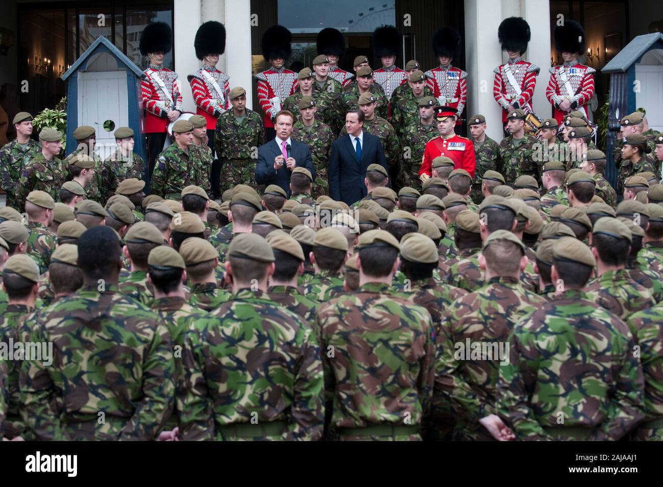 Il governatore della California Arnold Schwarzenegger e il Primo Ministro David Cameron con le truppe britanniche dal primo battaglione di guardie granatieri presso la caserma di Wellington a Londra. Foto Stock