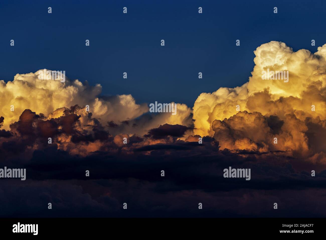 Cumulus nubi swirl in condizioni di luce solare intensa contro un cielo blu scuro in un pre-temporale atmosfera. Sfumature colorate di soffici nuvole Foto Stock