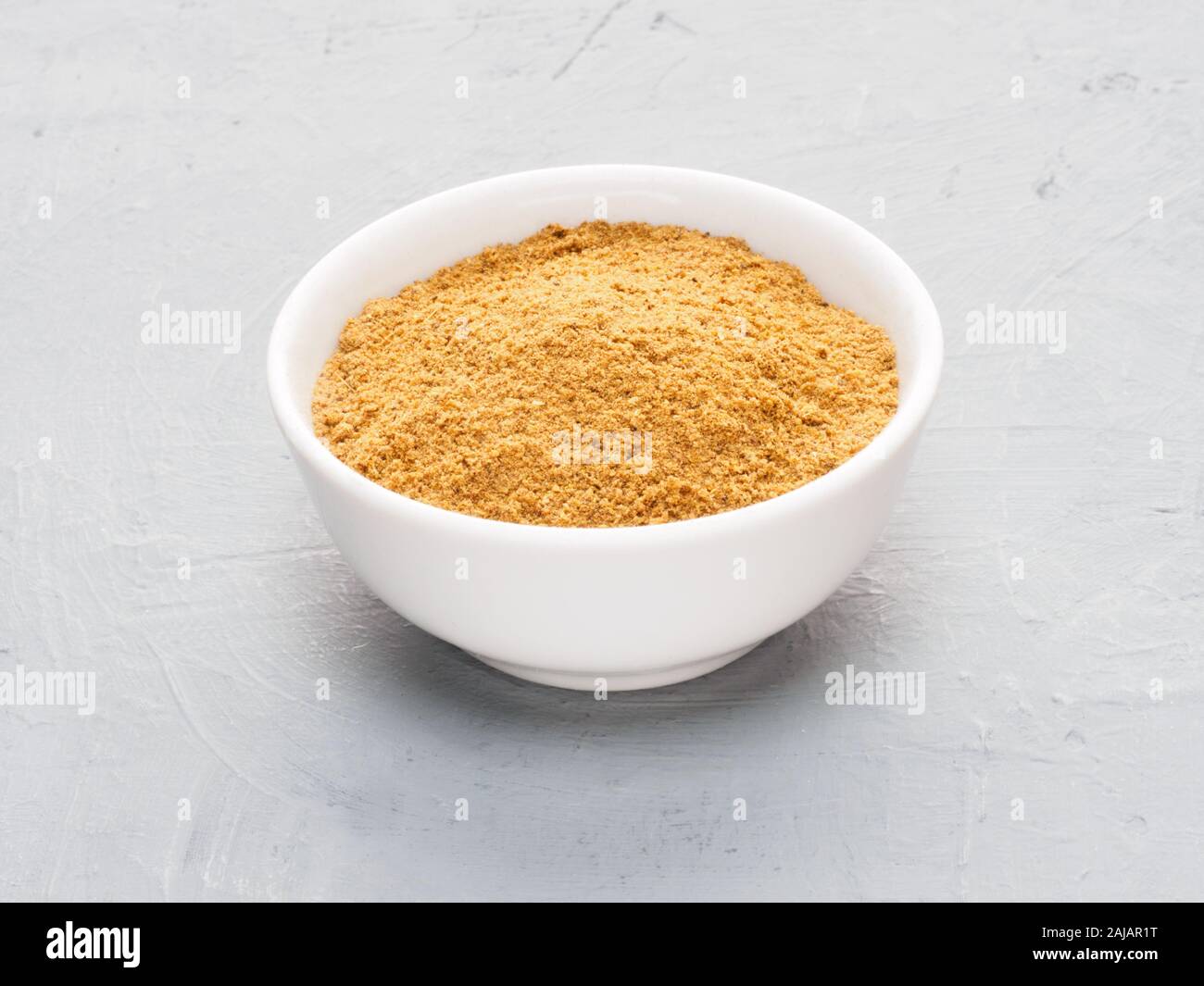 Spice masala in ceramica bianca cup sul cemento grigio Sfondo. Mangiare sano concetto Foto Stock