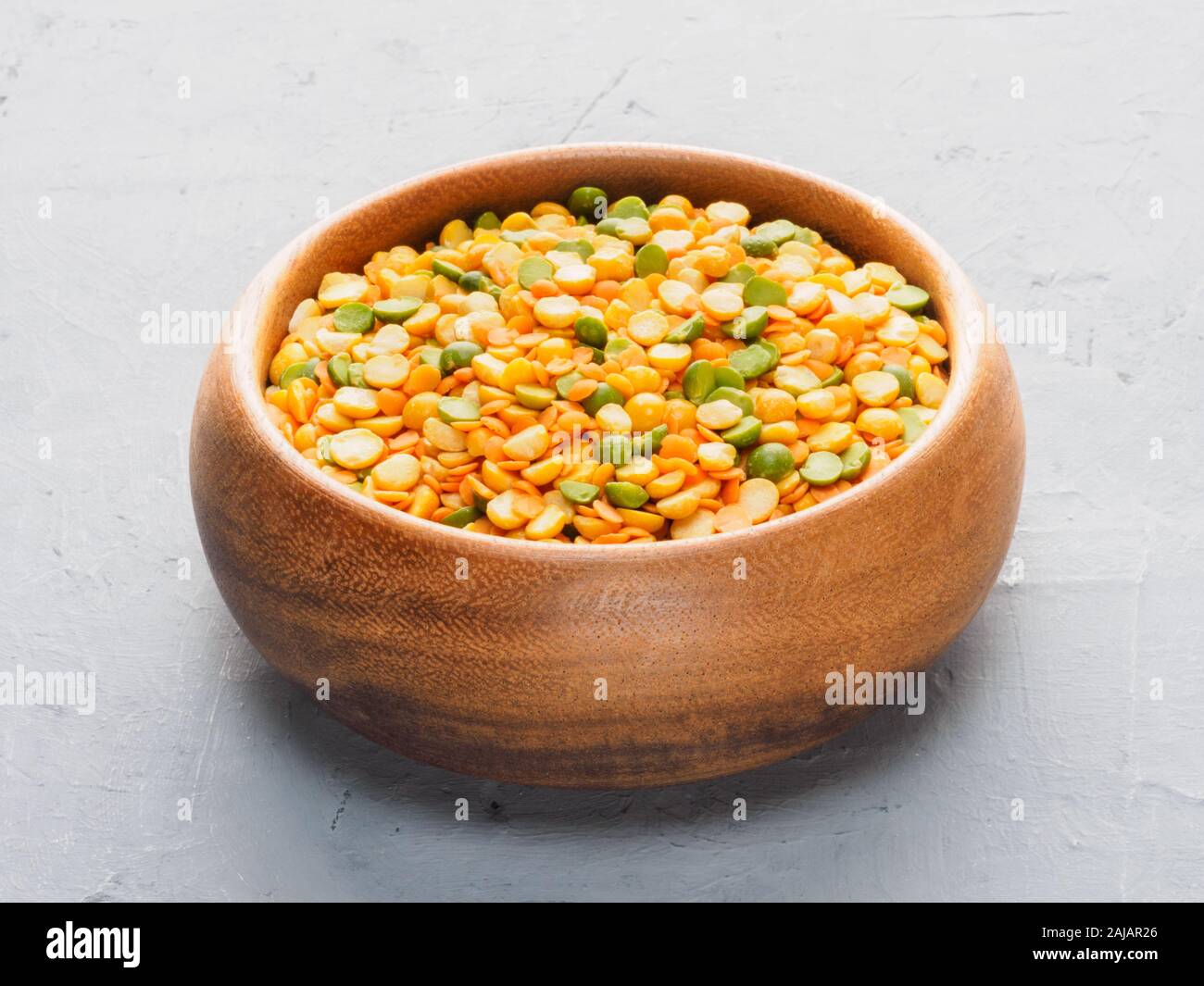 Il giallo e il verde pisello in tazza di legno sul cemento grigio e tessuto beige background. Dieta e perdita di peso concept Foto Stock