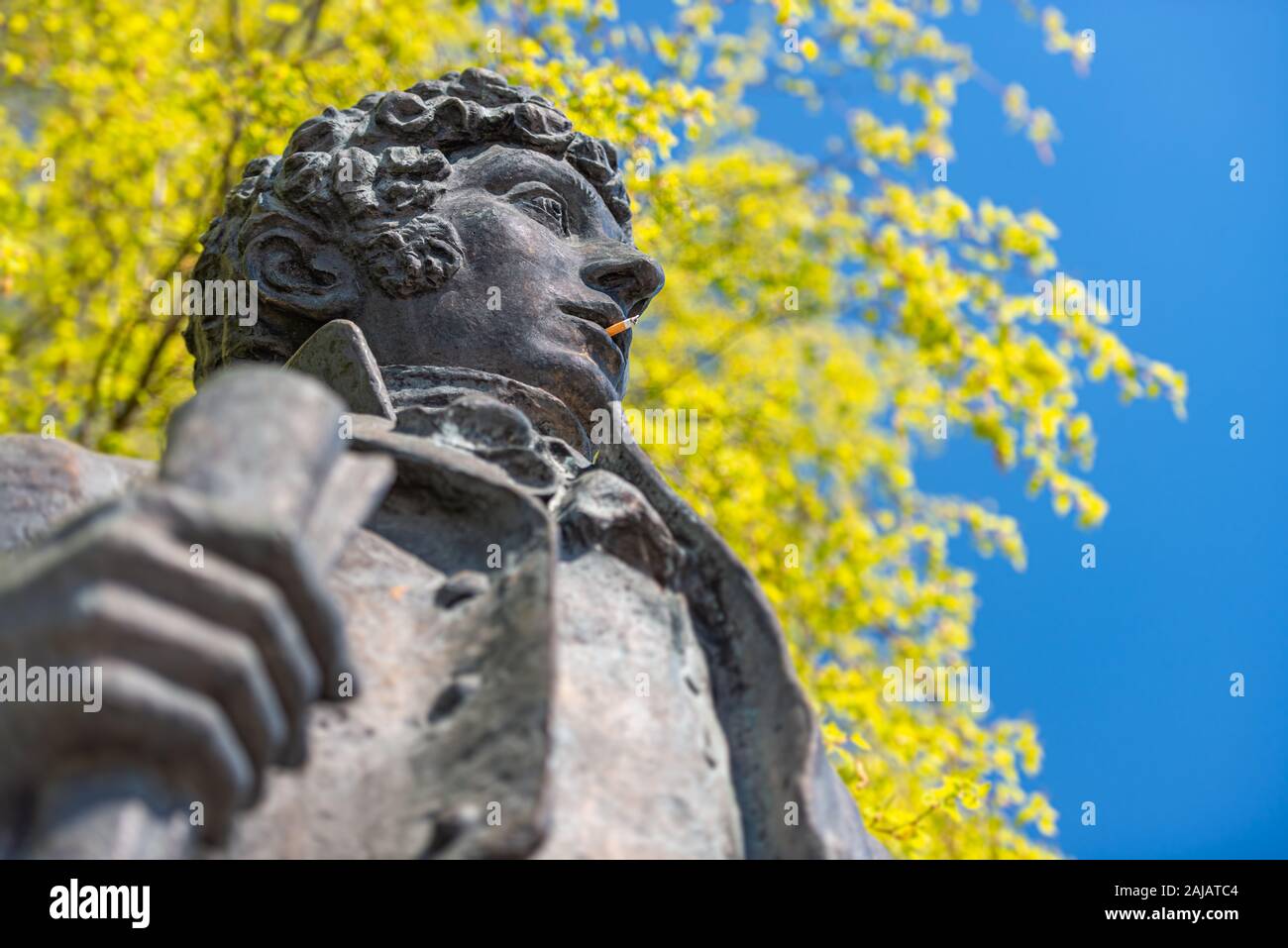 Un monumento di classici popolari poeta russo Pushkin. Cigaret in bocca e albero in background Foto Stock