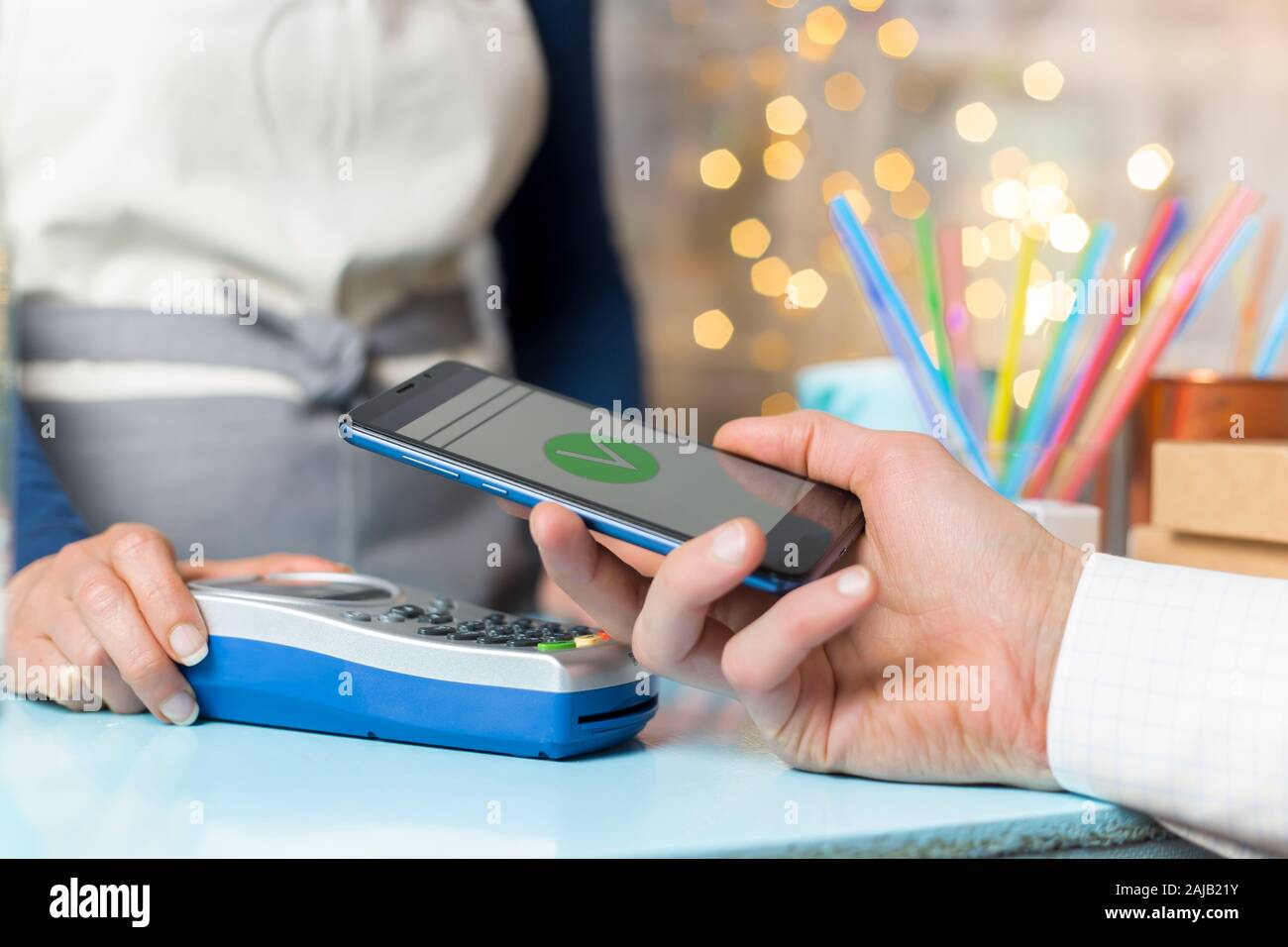 La mano del cliente paga con lo smartphone in negozio utilizzando la tecnologia NFC. Telefono cellulare a pagamento con contatto meno tecnologia. Foto Stock
