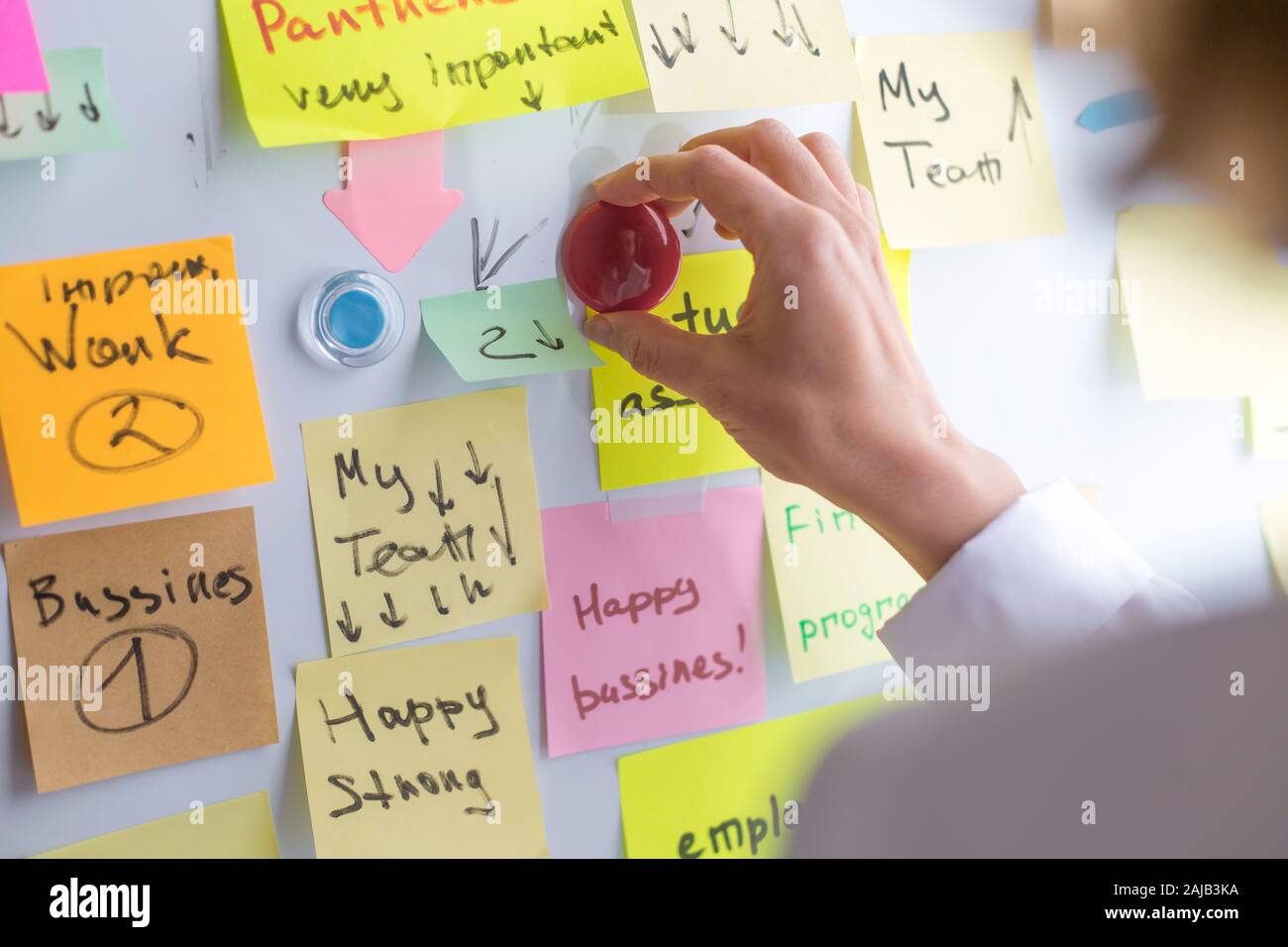Gli uomini d'affari scrivono una nota importante, usando sul posto degli adesivi di carta. Brainstorming, lavoro di squadra. Foto Stock