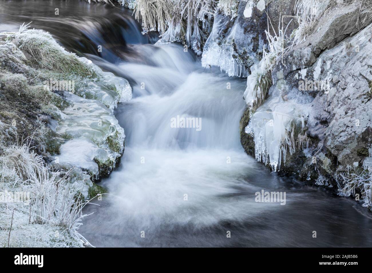 Fast ruscello che scorre con sovrastante ghiaccioli nel periodo invernale Foto Stock
