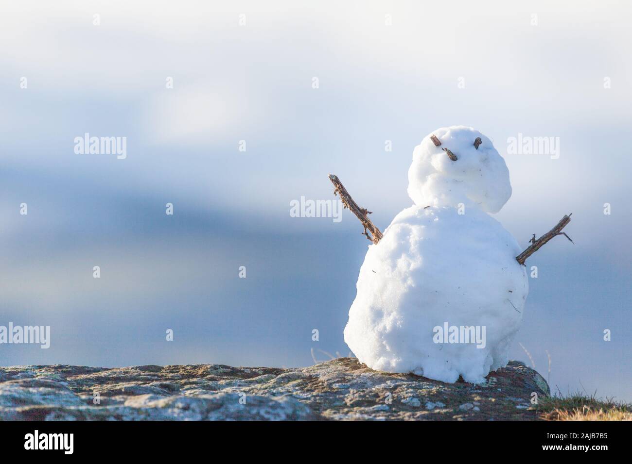 Piccolo uomo di neve costruito alla prima nevicata sulle falesie a Belford Moor guardando verso le colline Cheviot nel Northumberland in inverno. Foto Stock
