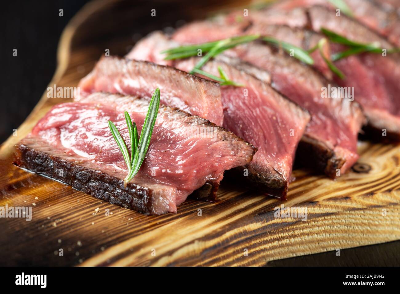 Succosa carne di manzo Costata di manzo fette leggermente salata, con erbe e spezie su tavola di legno. Dark sfondo nero Foto Stock