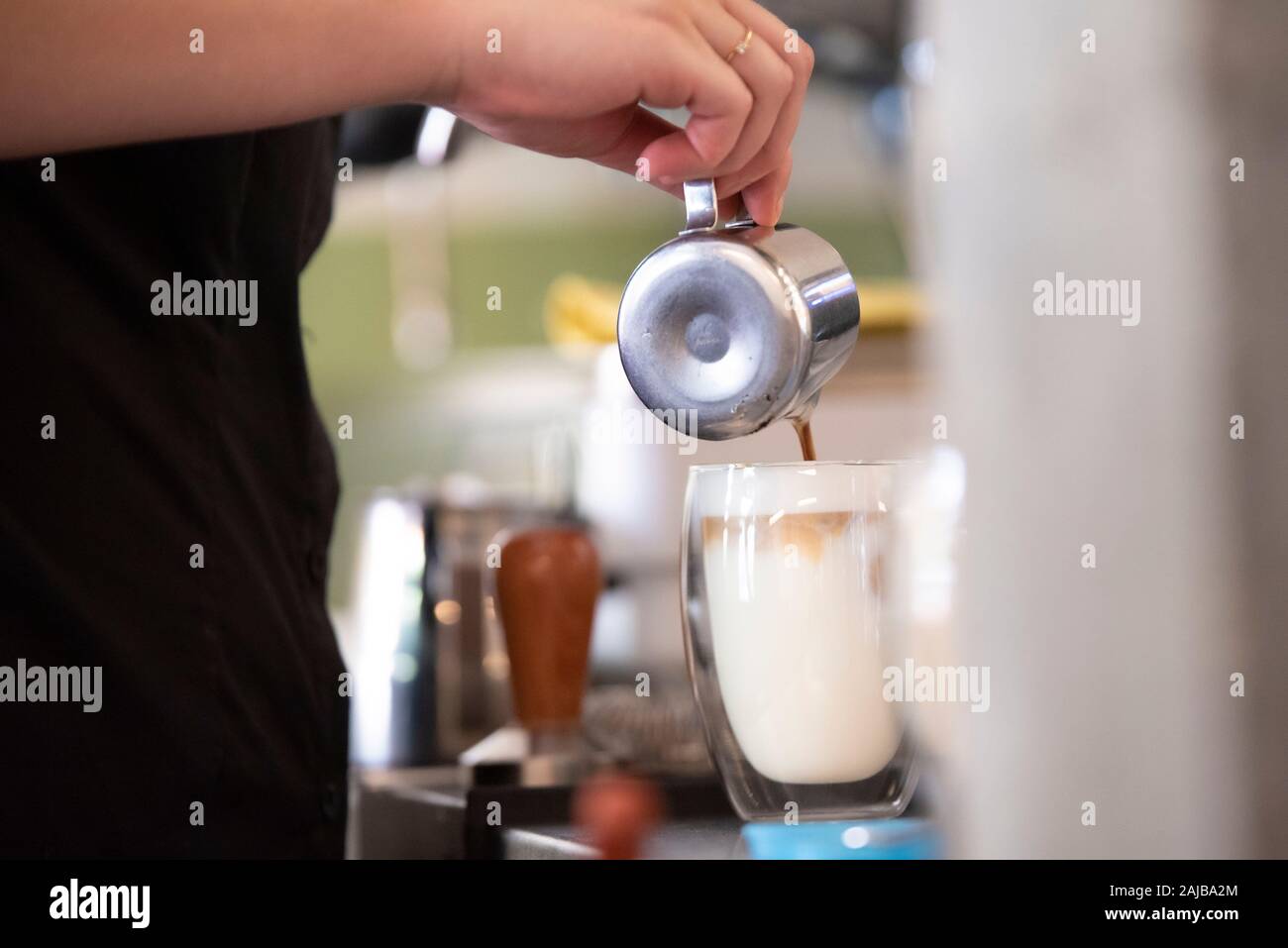 Immagine di azione di fare del caffè latte versando il latte in vetro Foto Stock