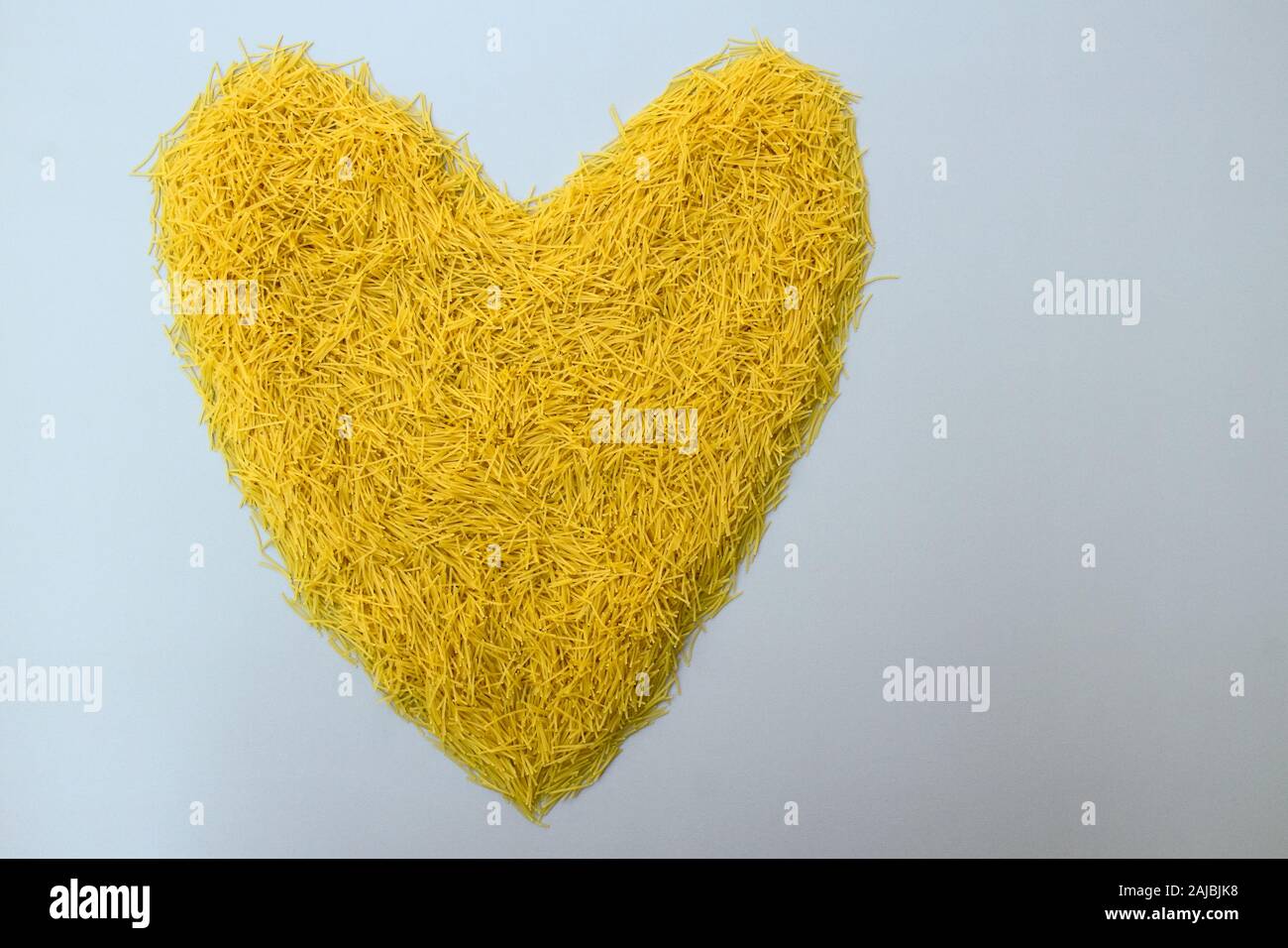 Giallo a forma di cuore la pasta italiana i vermicelli, vista dall'alto per un romantico ristorante menu design e il giorno di San Valentino saluti con copia spazio per il testo Foto Stock