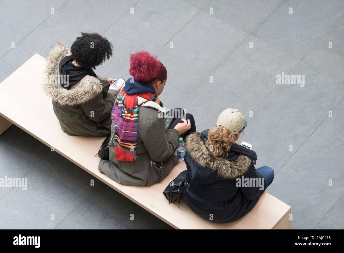 Tre giovani donne udienza del Bech su telefoni cellulari, NYC, STATI UNITI D'AMERICA Foto Stock