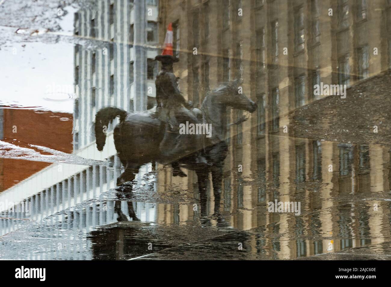 Il duca di Wellington statua con iconica cono di traffico si riflette sulla pozza in un giorno di pioggia a Glasgow, Scotland, Regno Unito Foto Stock