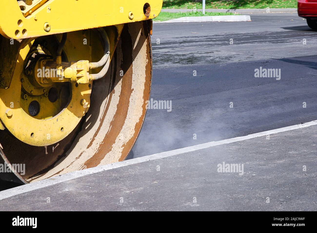 Lavori stradali in corso, asfalto caldo con vapore e rullo di strada sulla giornata di sole Foto Stock