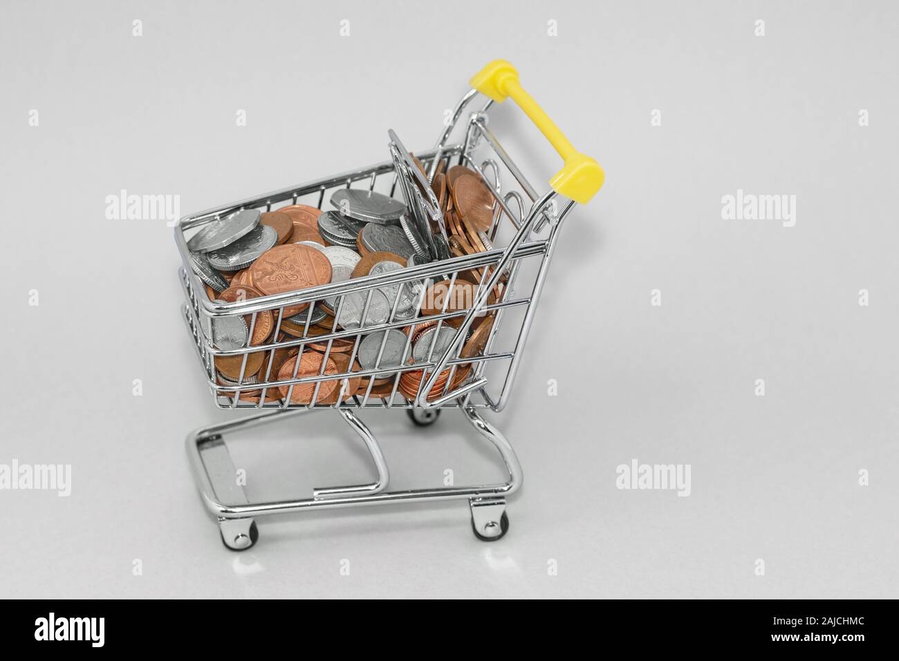 Carrello della spesa riempito con cambio allentata, british penny monete. Gli eccessi di spesa e di costo della vita concetto Foto Stock