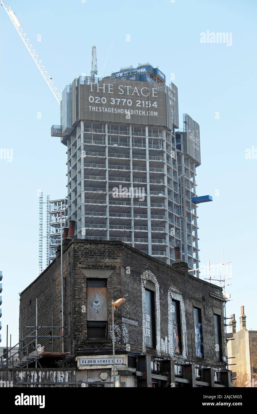 L'alto edificio a torre in fase di sviluppo della proprietà in costruzione vista verticale con edificio derelict Commercial Street East London E1 KATHY DEWITT Foto Stock