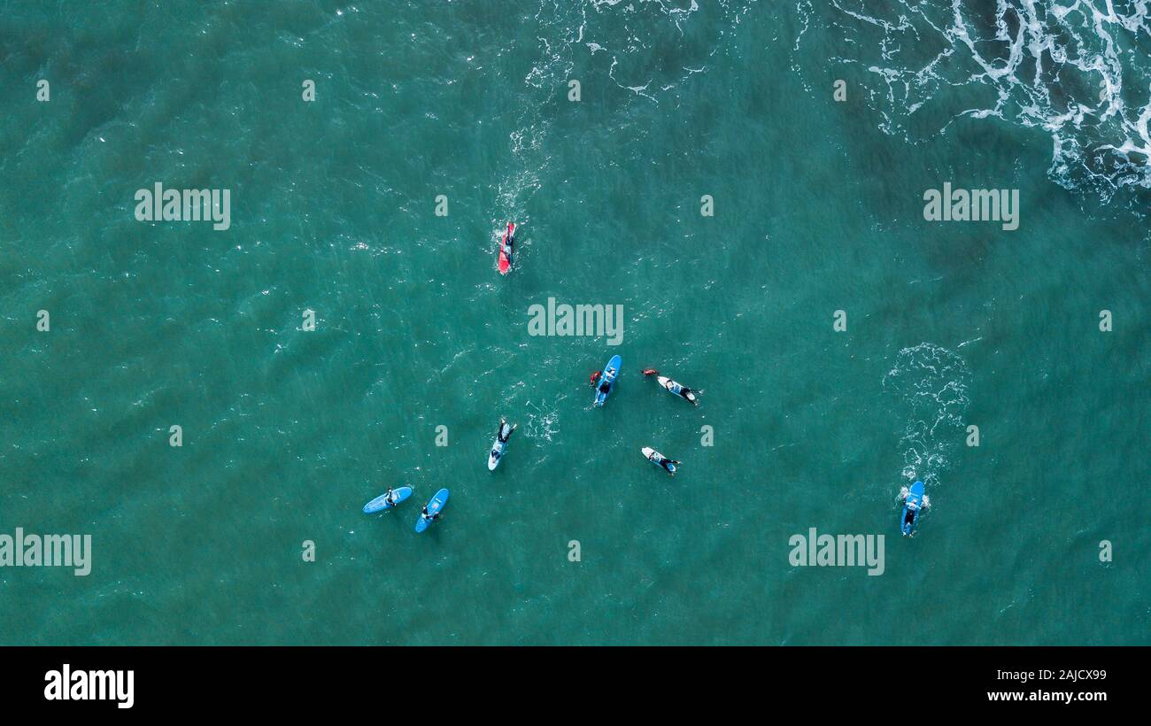 Vista aerea del surfer nuoto a bordo vicino enorme blu oceano onda nel Porto da Cruz, l'isola di Madeira, Portogallo Foto Stock