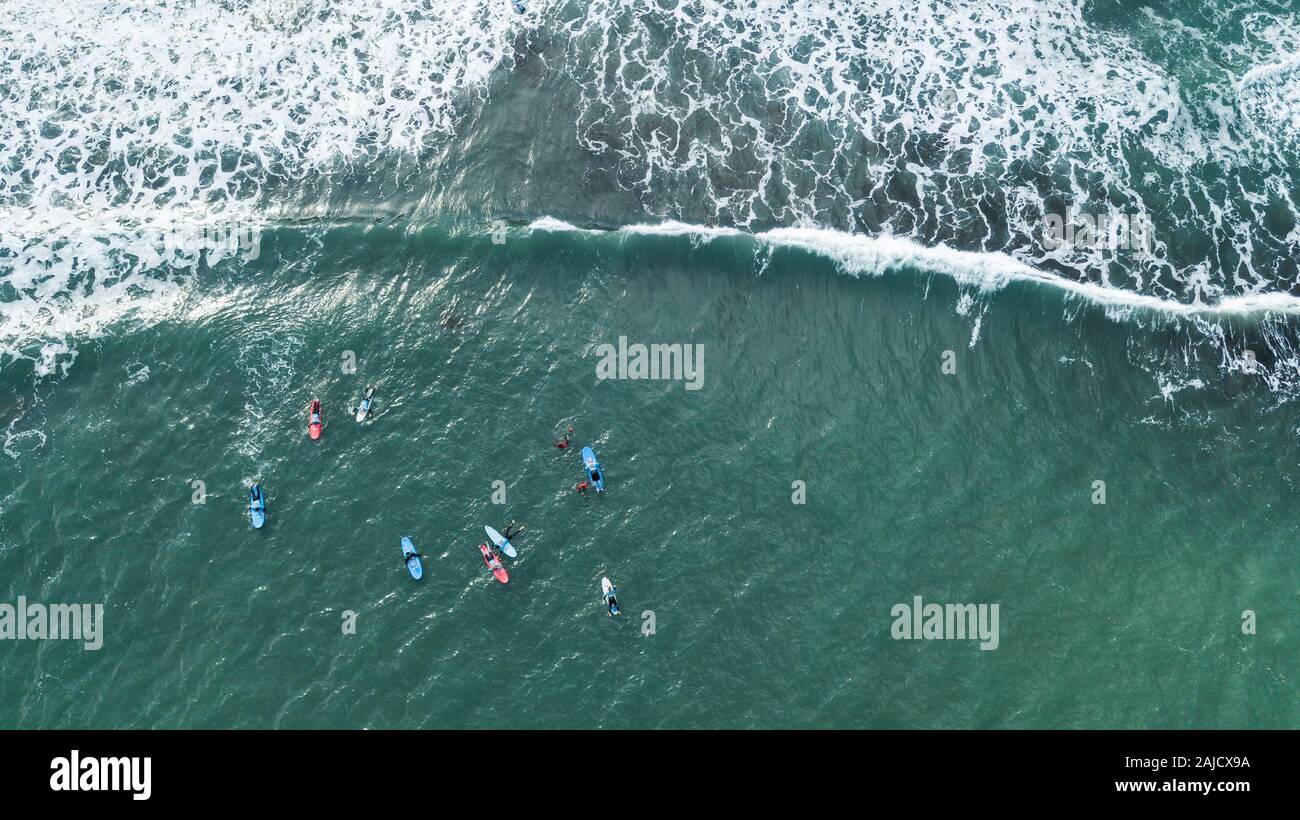 Vista aerea del surfer nuoto a bordo vicino enorme blu oceano onda nel Porto da Cruz, l'isola di Madeira, Portogallo Foto Stock