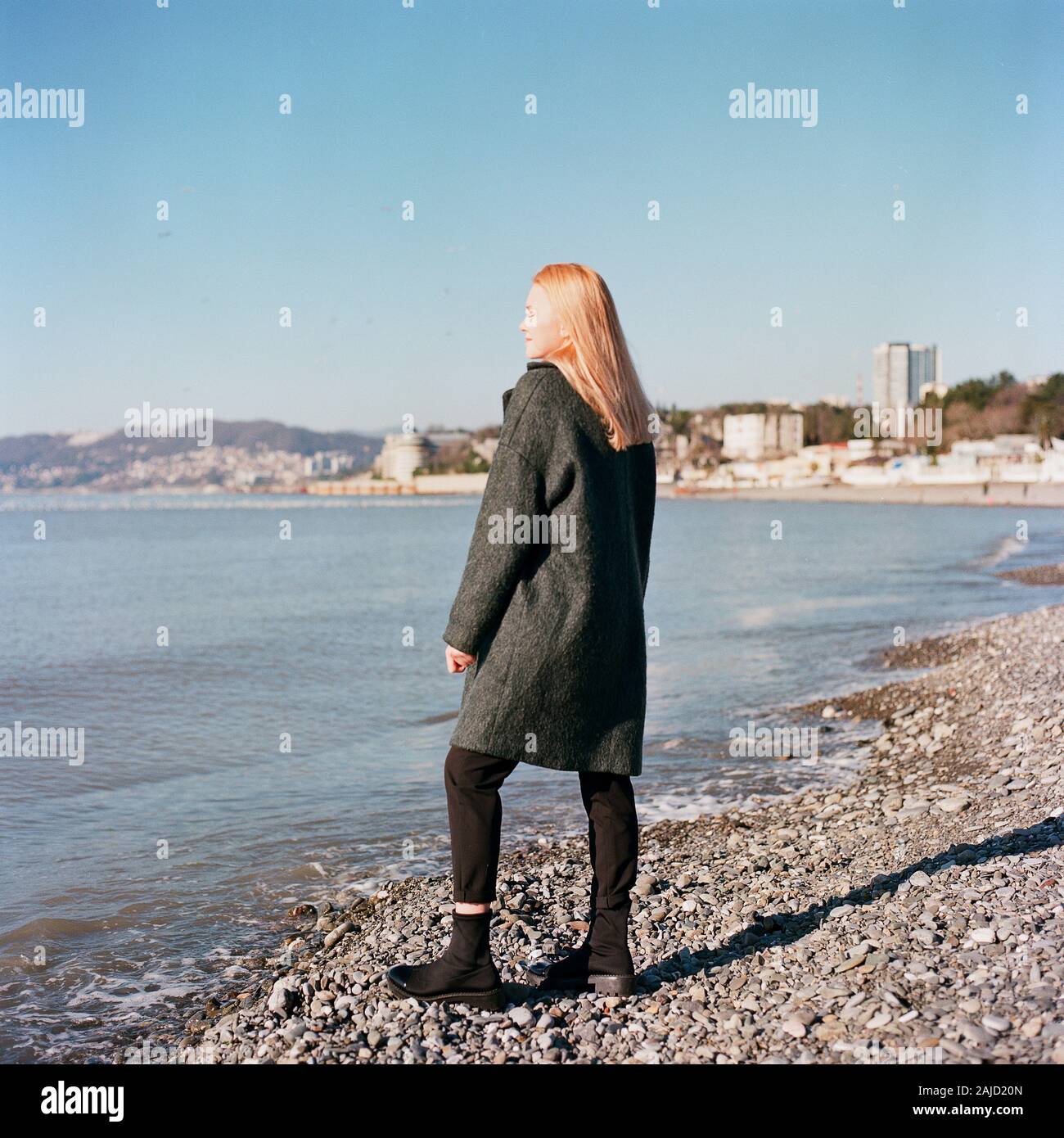 Una bella donna si erge vicino al mare e sorride Foto Stock