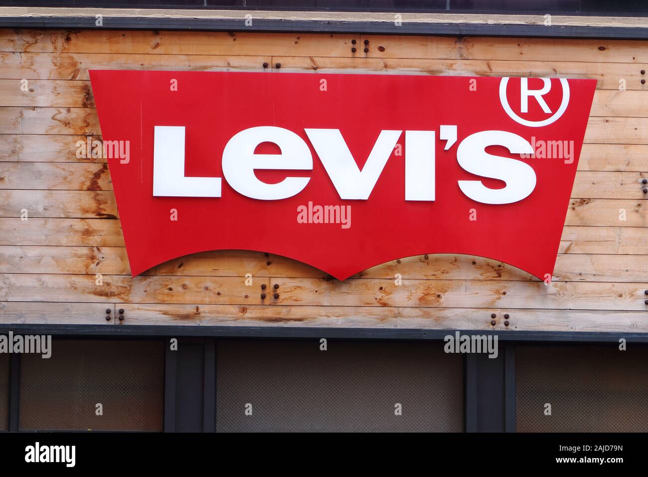 Il logo rosso della Levi's set contro il rivestimento di pannelli di legno presso il proprio negozio in Herald Square a Manhattan, New York, NY. Foto Stock