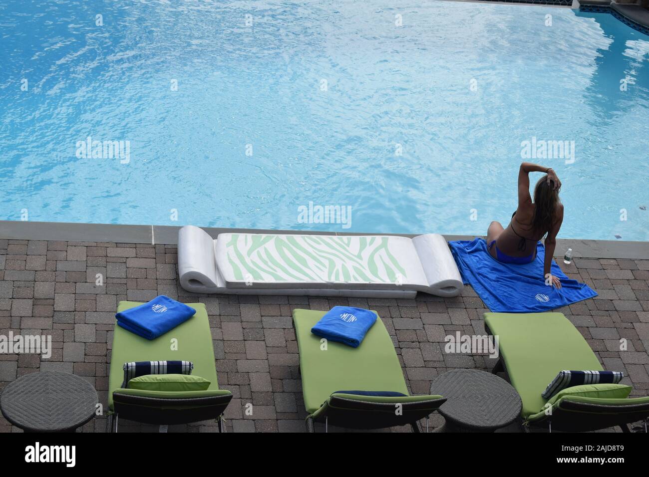 Un nuotatore con capelli bagnati in un bikini si siede da una piscina blu. Foto Stock