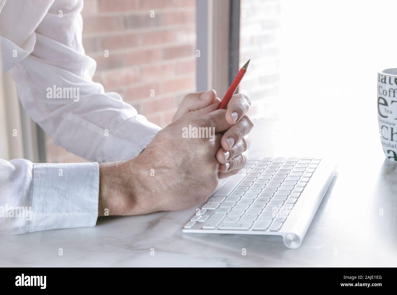 Nella parte anteriore della sua tastiera, nelle mani di un uomo con una penna rossa. Foto Stock