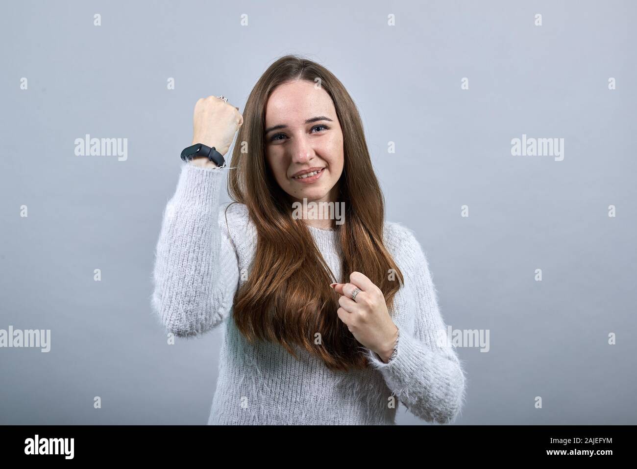 Caucasian donna attraente in un maglione mantenendo i pugni fino, dancing, pronto per la lotta Foto Stock