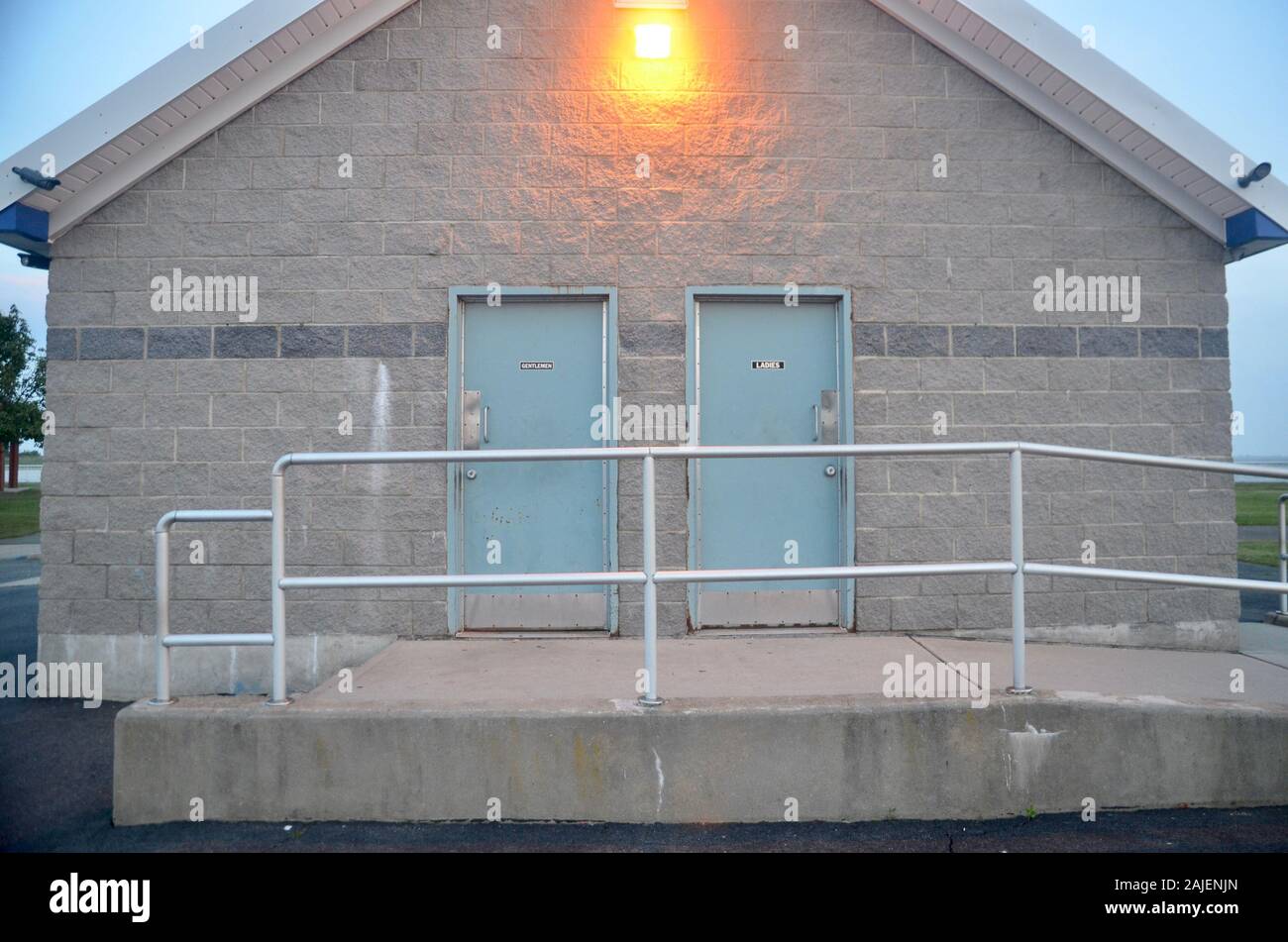 Un blocco di cemento armato edificio con due bagno verde porte dichiarando gentleman e colleghe. Foto Stock