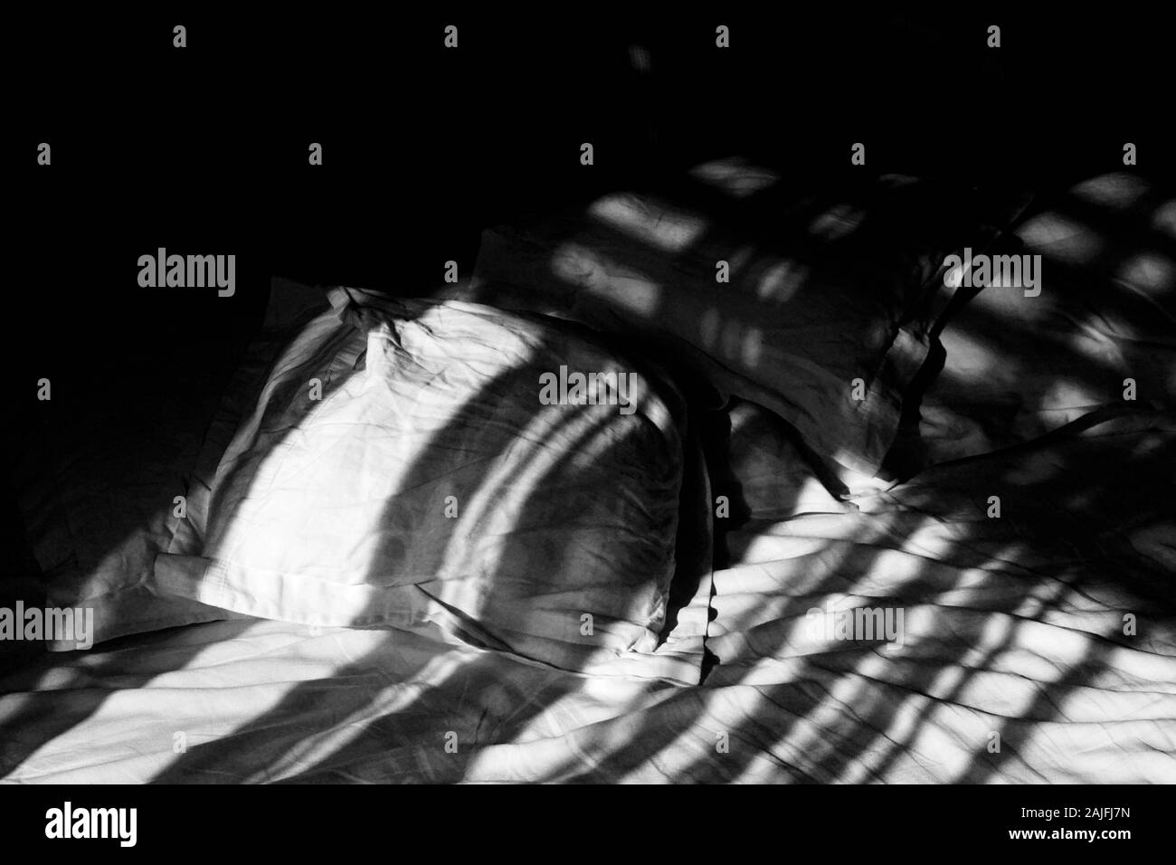 Camera da letto in scena con la biancheria bagnata nella luce del mattino. Bella luce sul cuscino e fogli di un letto vuoto e un libro aperto. Foto Stock