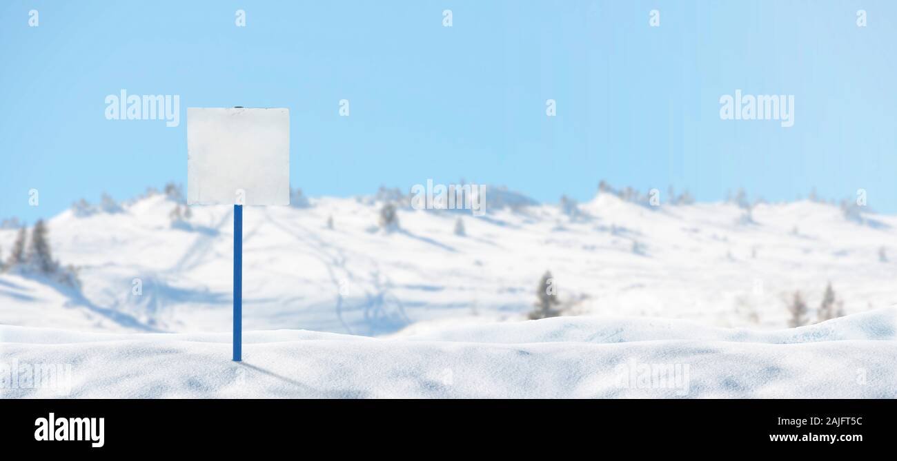 Segno bianco per sciatori su una pista da sci imperniata alla neve mockup. Copia spazio accanto. Piste da sci e cime innevate sullo sfondo Foto Stock