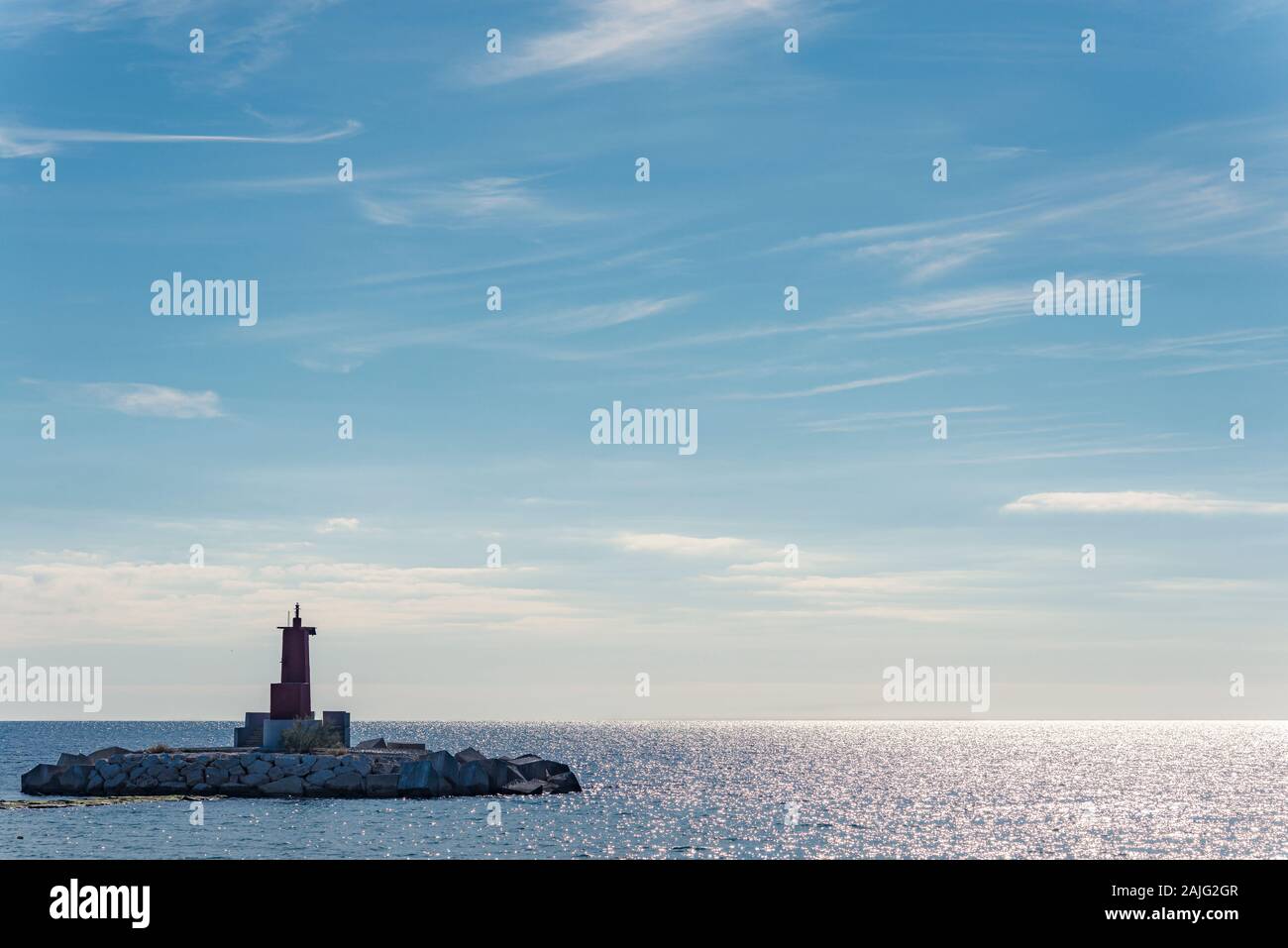 Luce rossa del porto al molo in una calda giornata nuvolosa sul mare Foto Stock