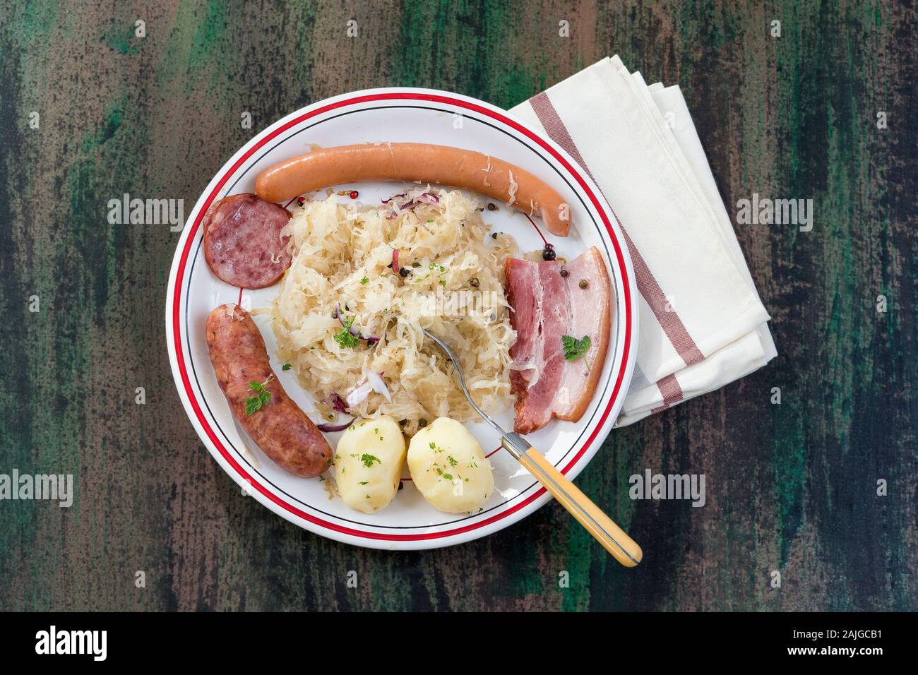 Choucroute garnie, una tipica piastra alsaziano, con salsicce, pancetta, i crauti e patate su sfondo di legno Foto Stock