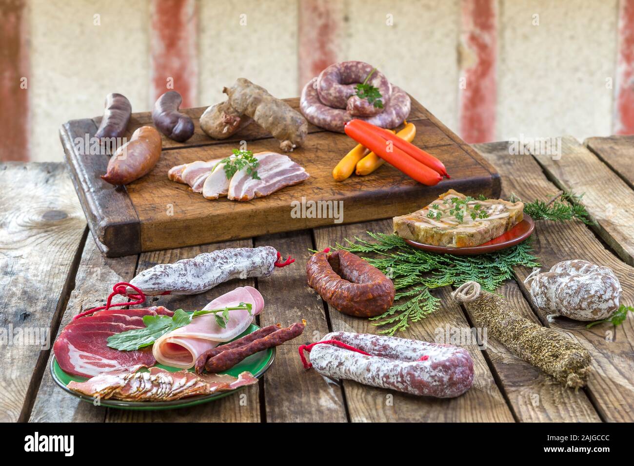 Selezione delle materie francese di salumi di bordo, con foglie di rucola e salsiccia secca sopra il vecchio rosso parete in legno sfondo. Foto Stock