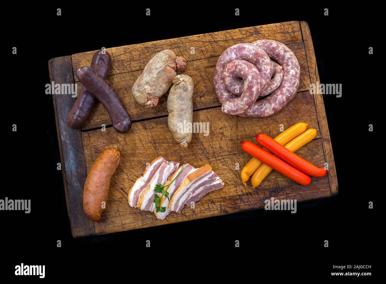 Selezione di francese insaccato crudo con parsleyon una tavola di legno,nero su sfondo l. Foto Stock
