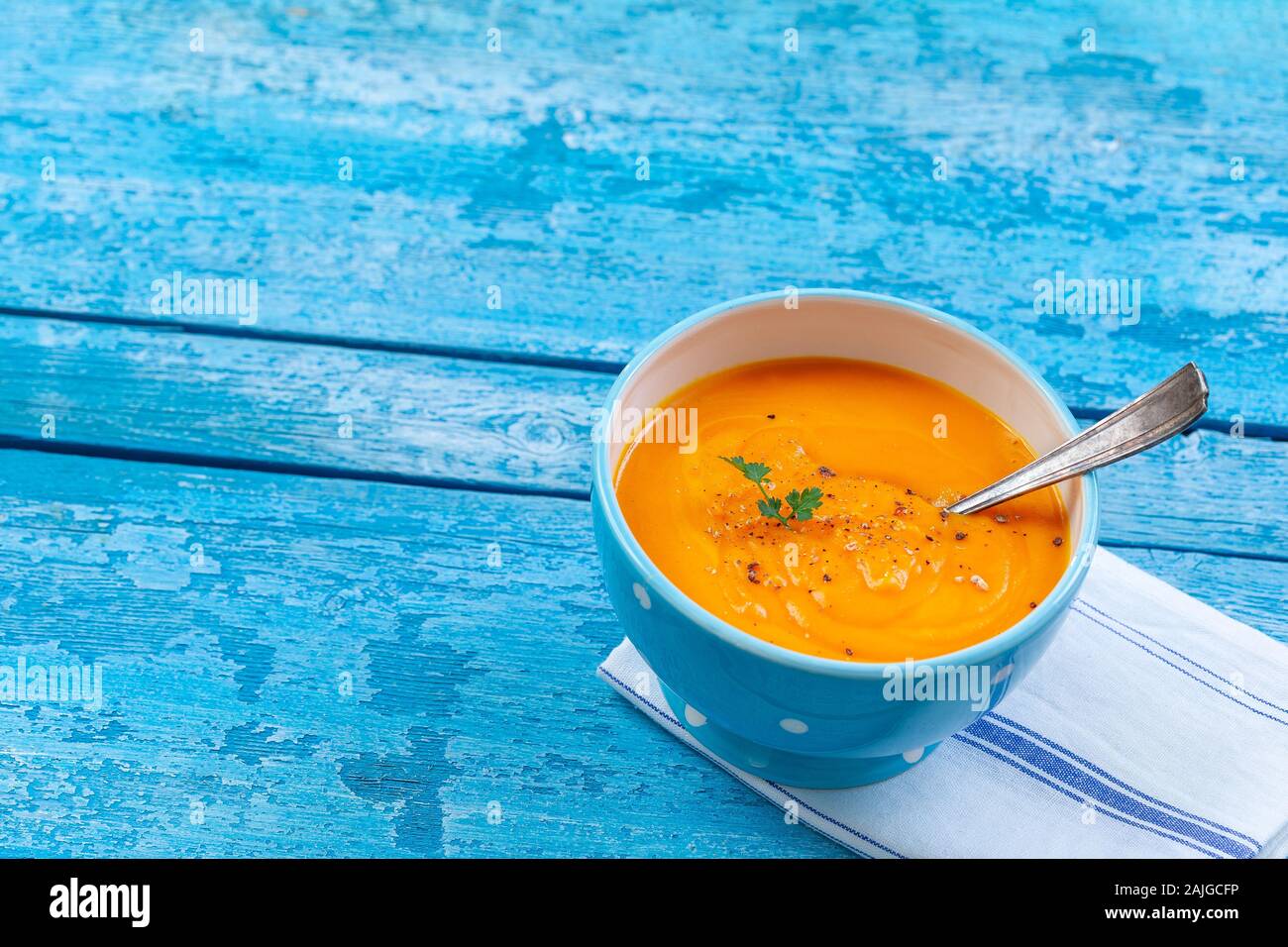 Salsa speziata zuppa di carote con crema e erbe aromatiche fresche blu tavolo in legno Foto Stock