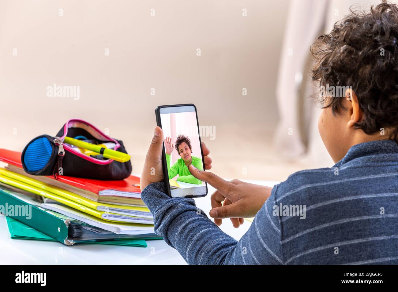 Studente ragazzo con lo smartphone a distrarre dallo studio. teen giocando a casa invece di fare i compiti di scuola Foto Stock