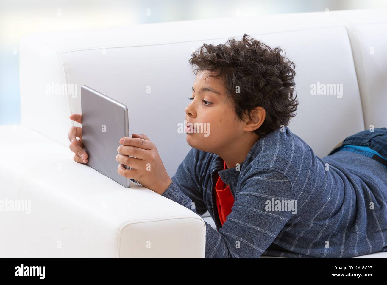 Giovane ragazzo adolescente utilizzando un tablet PC con una seria intenzione expression Foto Stock